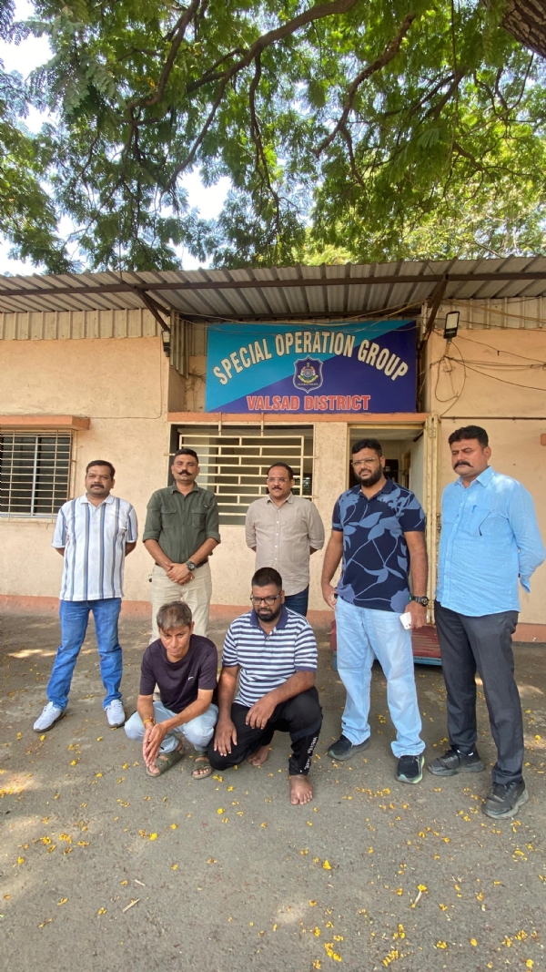 વલસાડ SOG ઓફિસ સામે નકલી પાસપોર્ટ રેકેટમાં ઝડપાયેલા બે આરોપીઓ સાથે પોલીસ ટીમ.